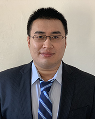 A portrait of Xiaolong Guo shows him wearing glasses in a navy blue suit jacket with a light and dark blue striped tie.