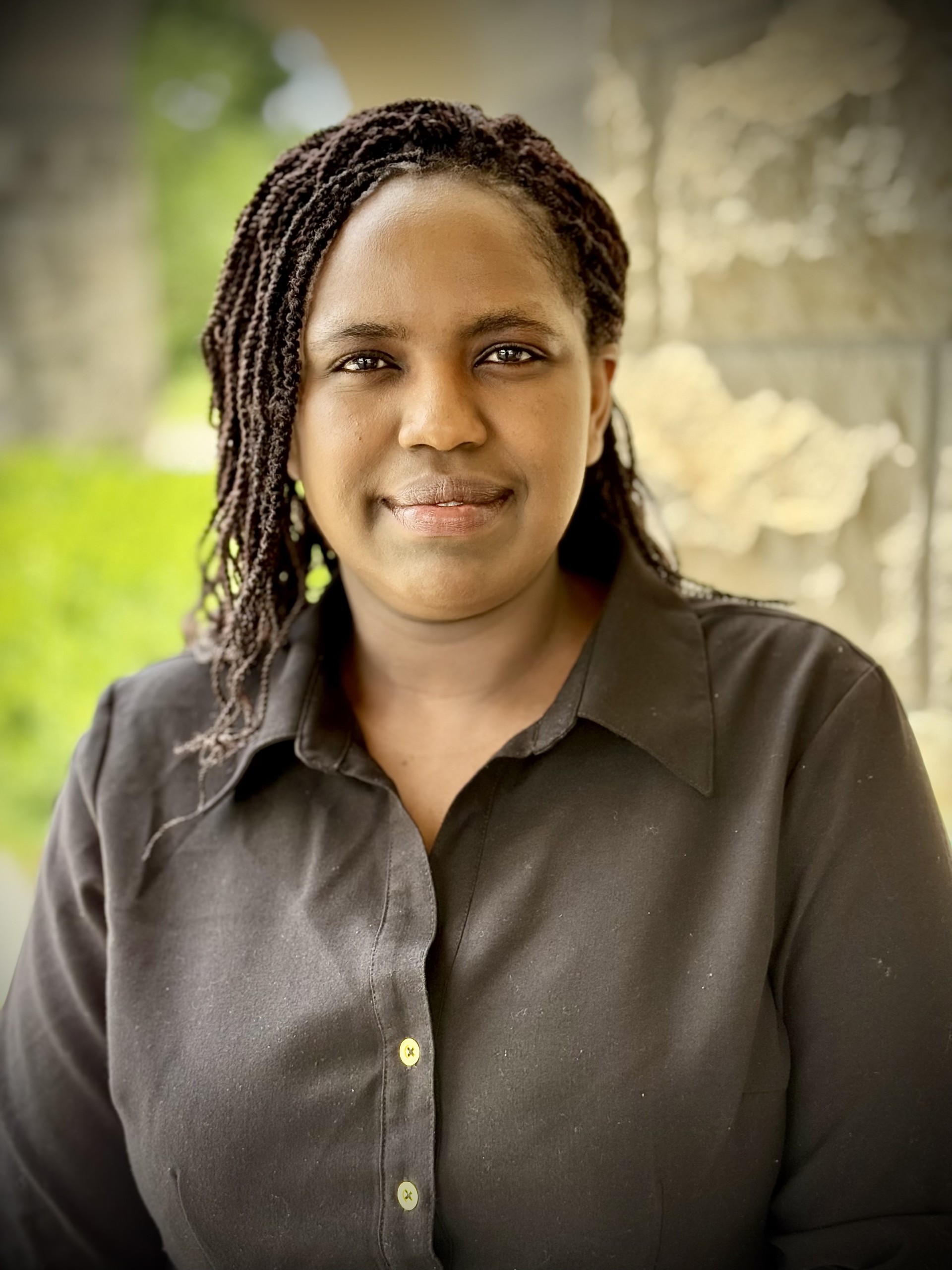A student in a dark gray shirt smiles for a portrait outdoors against a limestone wall.