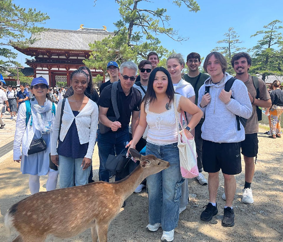 A group of people smiles for a photo with a deer
