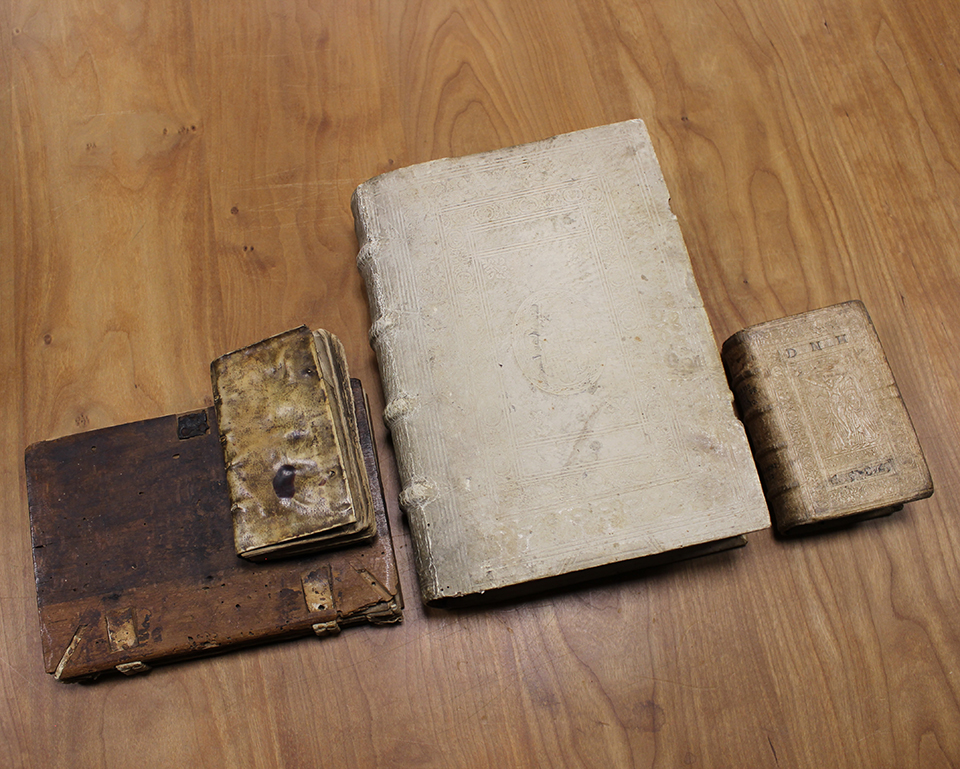 A set of several books without bindings set on a wooden table.