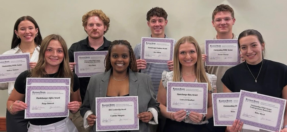 Two rows of students hold up award certificates and smile for a group photo.