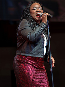 Woman singing into a microphone on stage