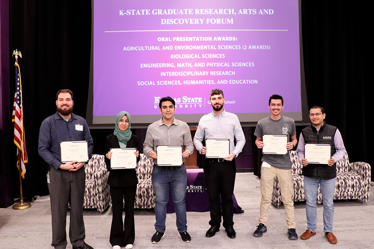 A group of people holding certificates standing in front of a purple screen.