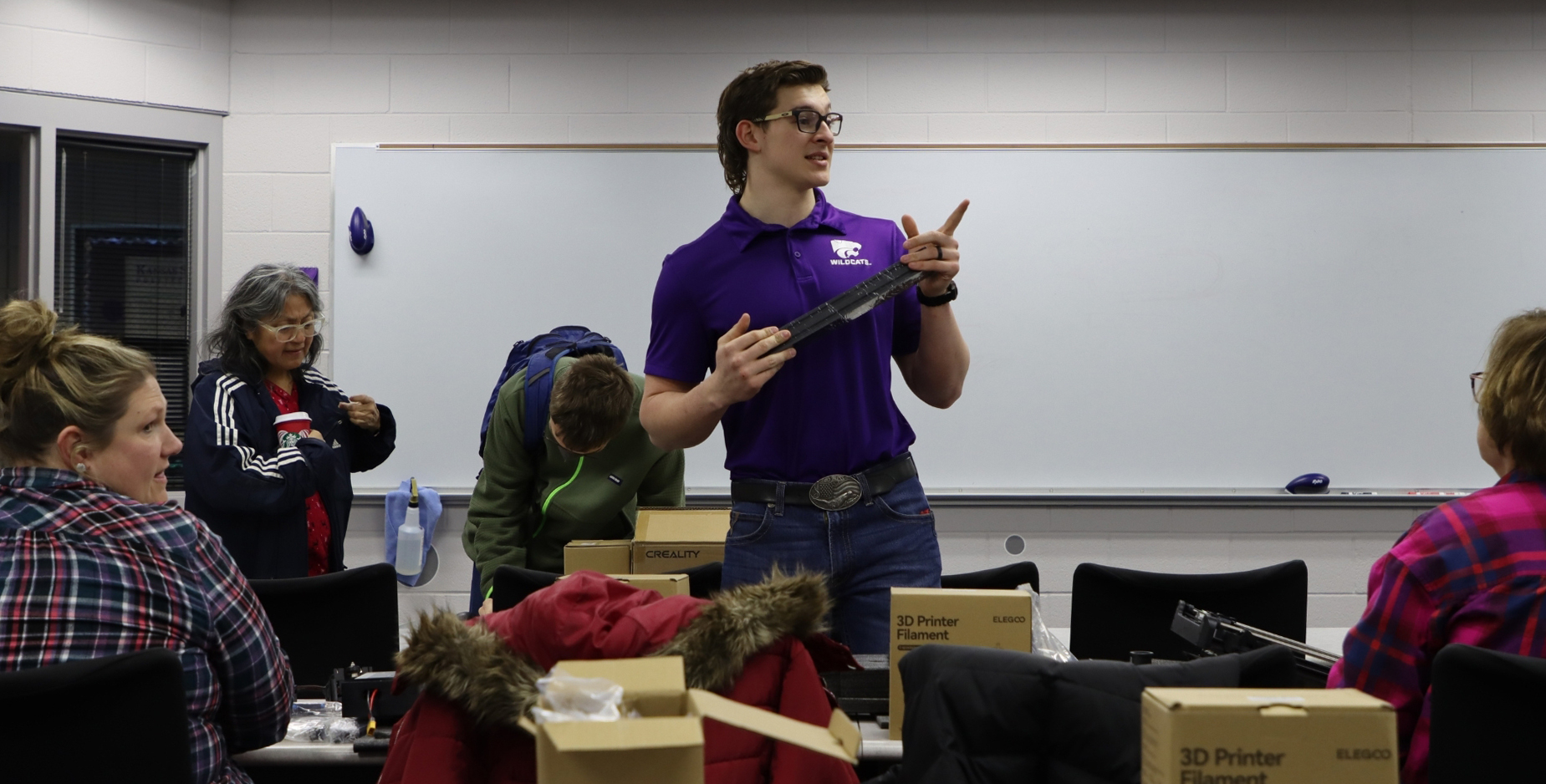 A student in a purple polo talks to participants in a 3D printing course