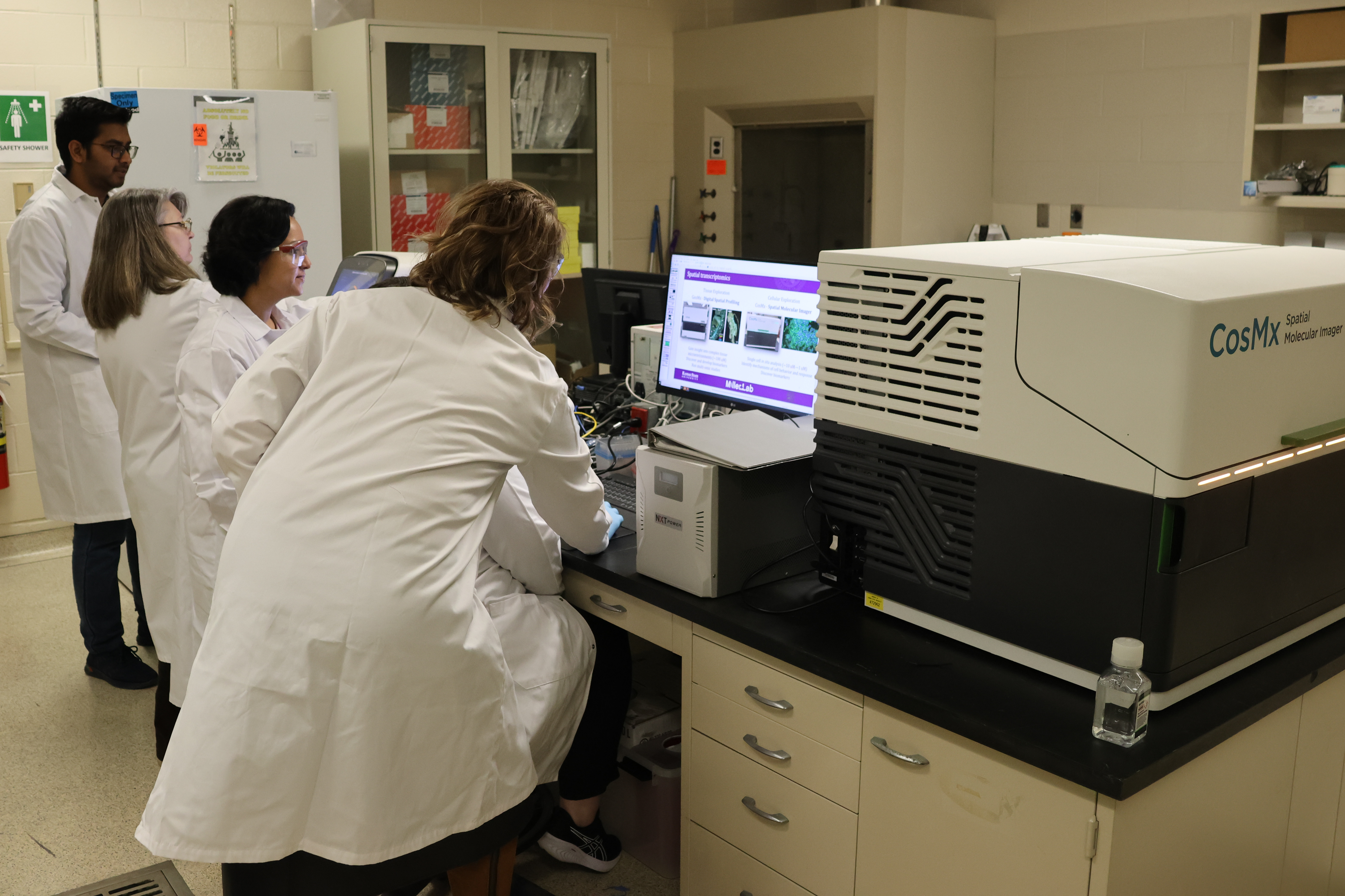 A group of researchers in white coats collaborating around a computer.