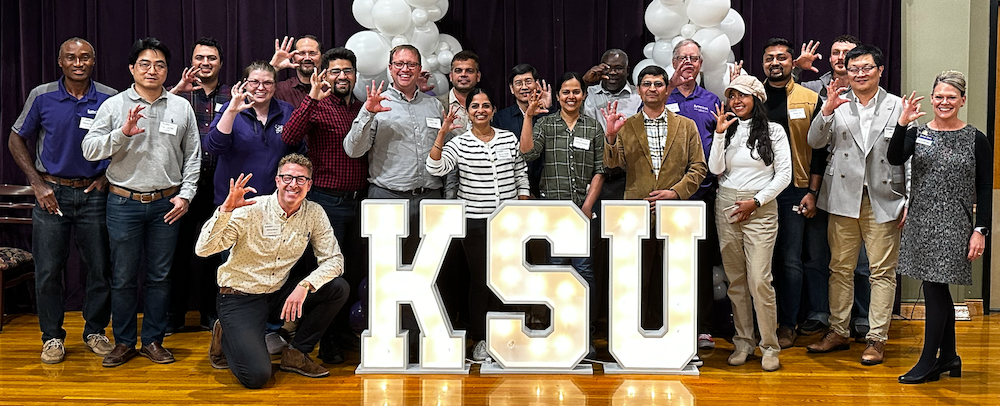 A group of faculty members around lit-up KSU letters