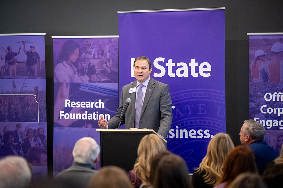 A man presents on a stage in front of a crowd.