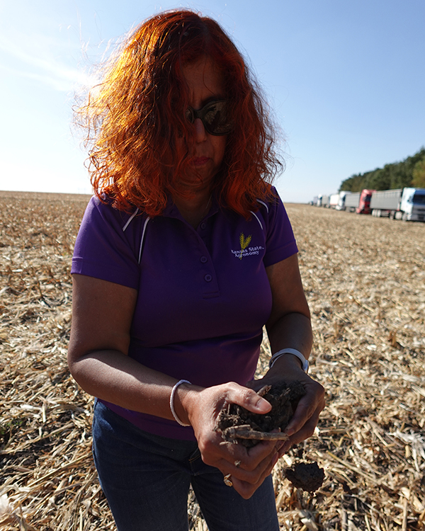 Ganga Hettiarachchi stands in a recently harvested corn field, holding up a clump of Ukrainian soil.