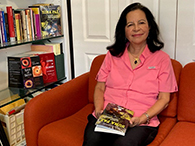 A-woman-sitting-on-an-orange-couch-holding-a-book