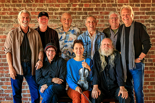 A group of people standing against a brick wall.