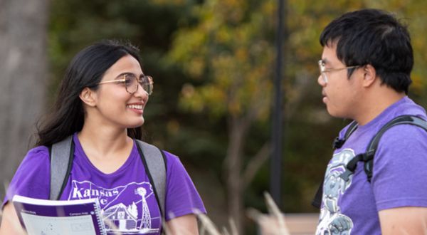 A female and male student in K-State t-shirts having a conversation