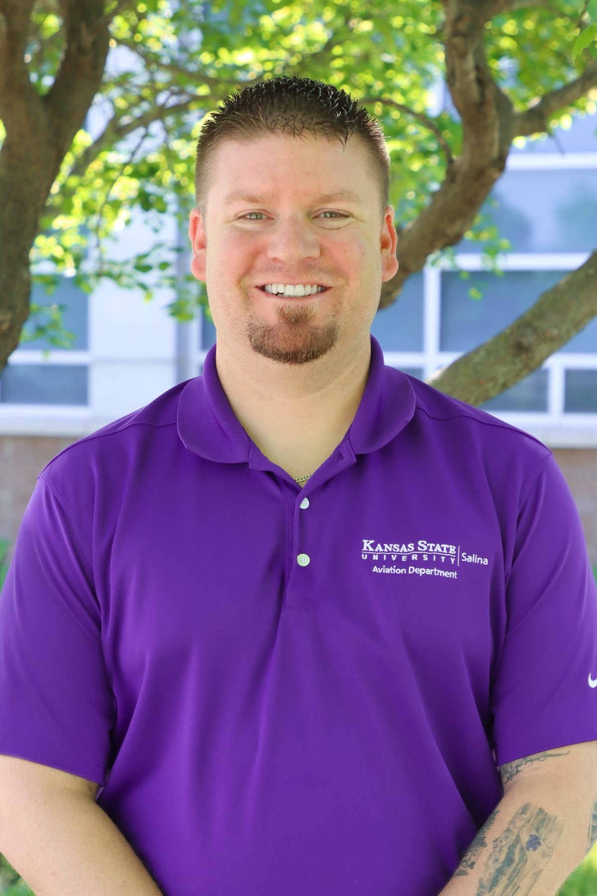 A white man in a purple K-State Salina polo smiles for a portrait photo.