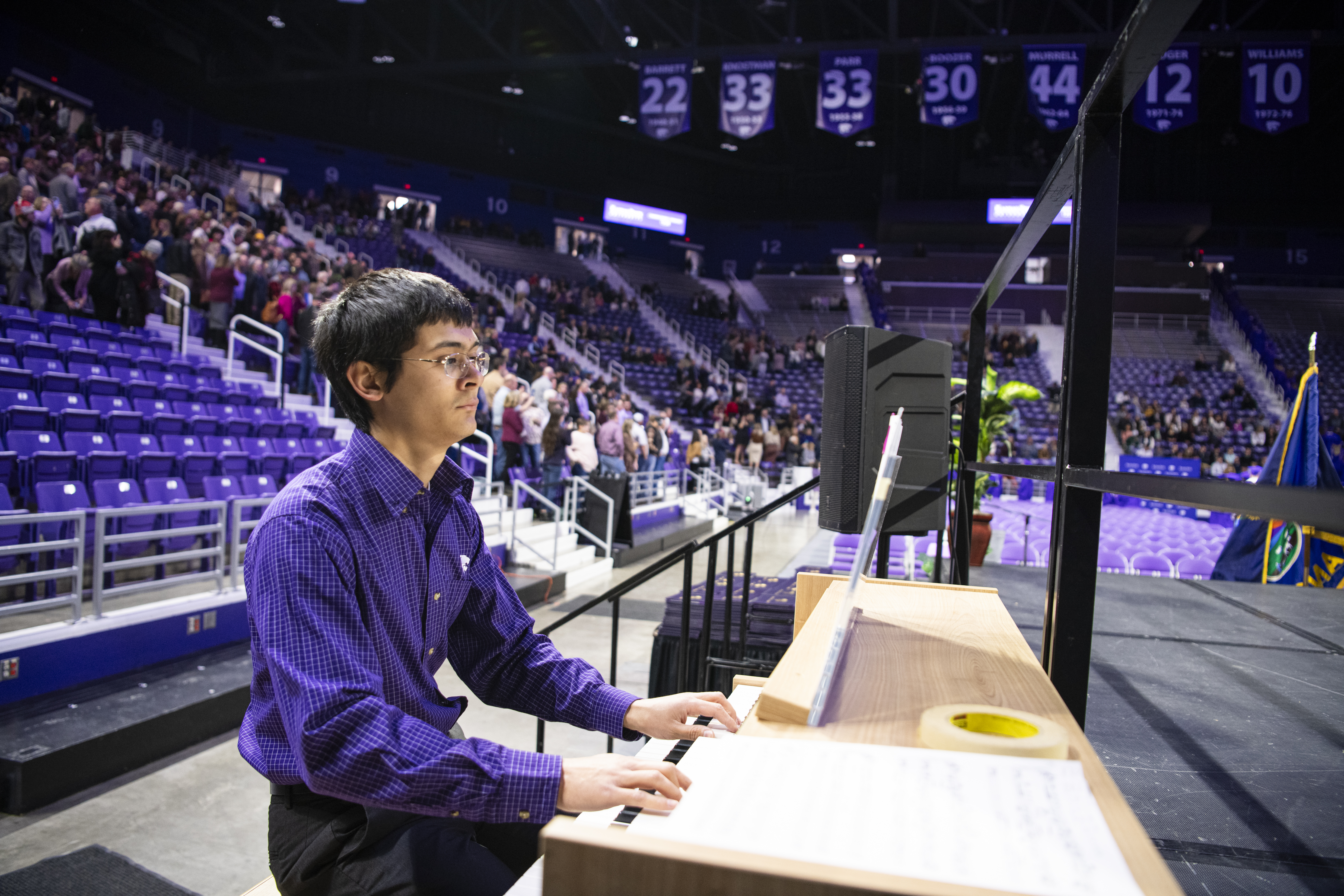 A student in a purple shirt playing the organ at commencement.