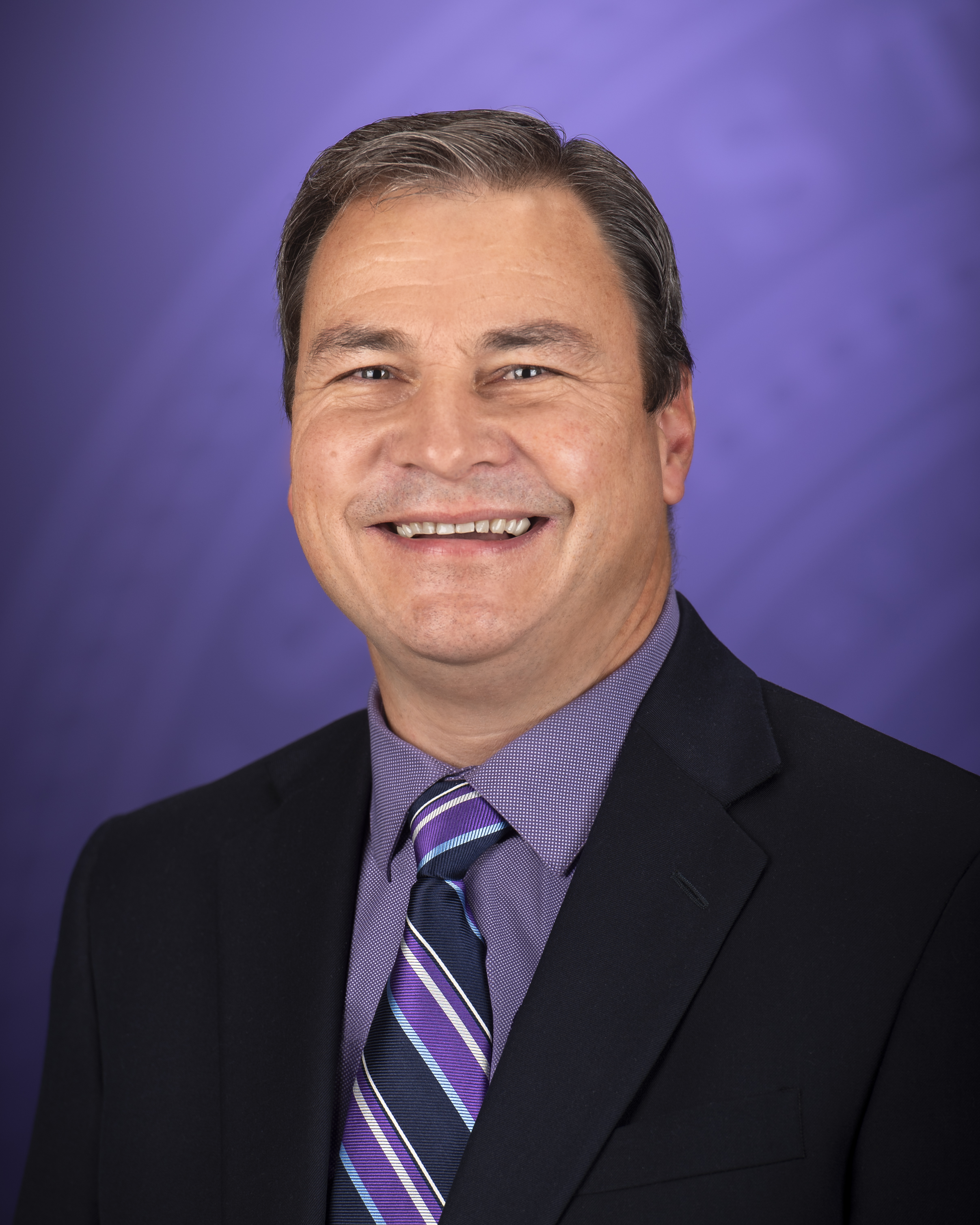 Hans Coetzee poses for a portrait in front of a purple backdrop.