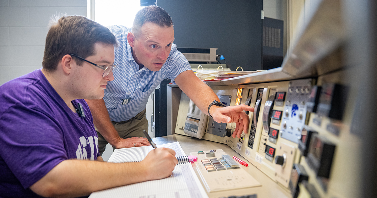 Amir Bahadori points to buttons on the nuclear reactor's control panels