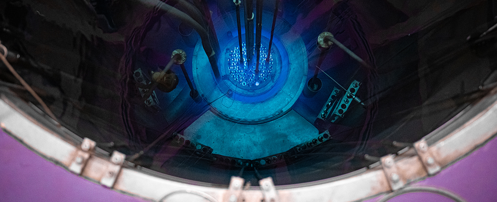 A top-down shot of a nuclear reactor shows a glowing blue core under a pool of dark water.
