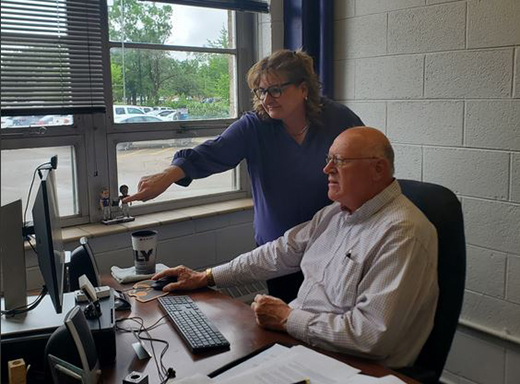 a-woman-pointing-at-something-on-a-computer-operated-by-a-man