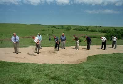 golfers hitting balls in sand pit