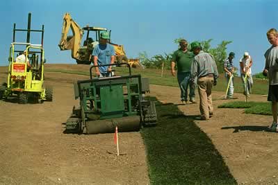 guy uses machine to lay sod on the ground