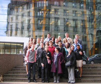 students in front of glass building with older building in reflection