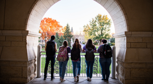 Students with their backs to the camera look out at campus.