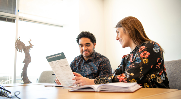 A person shows another person a resources on a piece of paper.