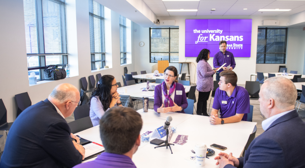 A group of K-Staters sit around a table in discussion.