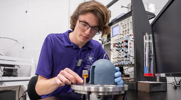Male student in purple polo conducting lab research