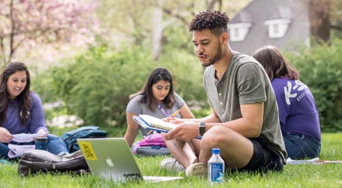 K-State student studying outside on lawn