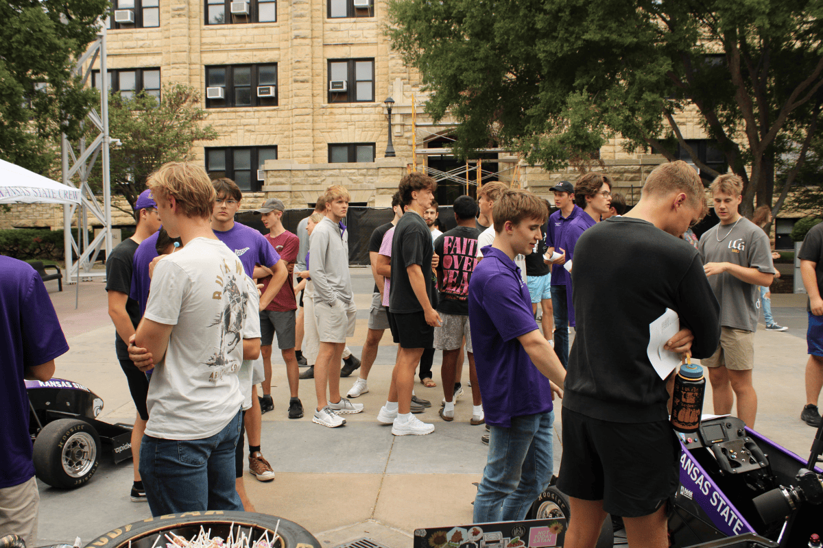 A large crowd gathers around the team to learn more