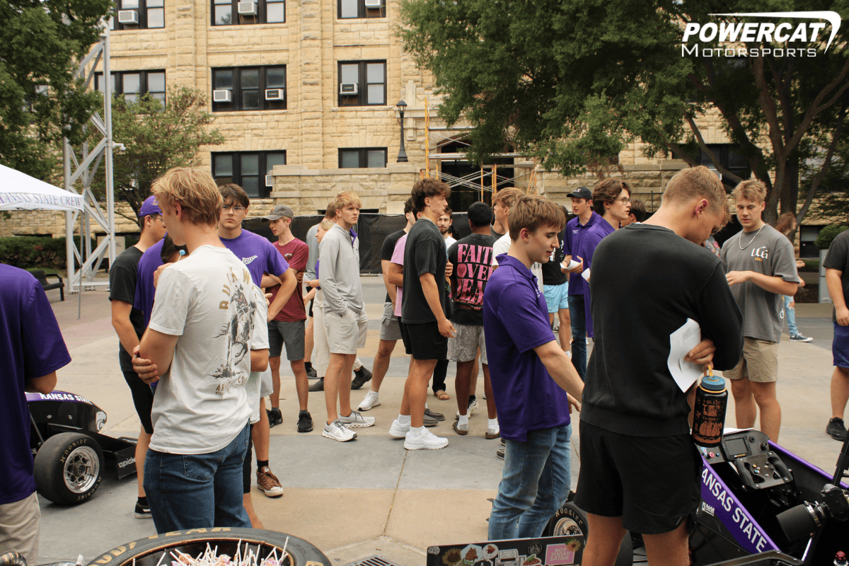 A large crowd gathers around the team to learn more