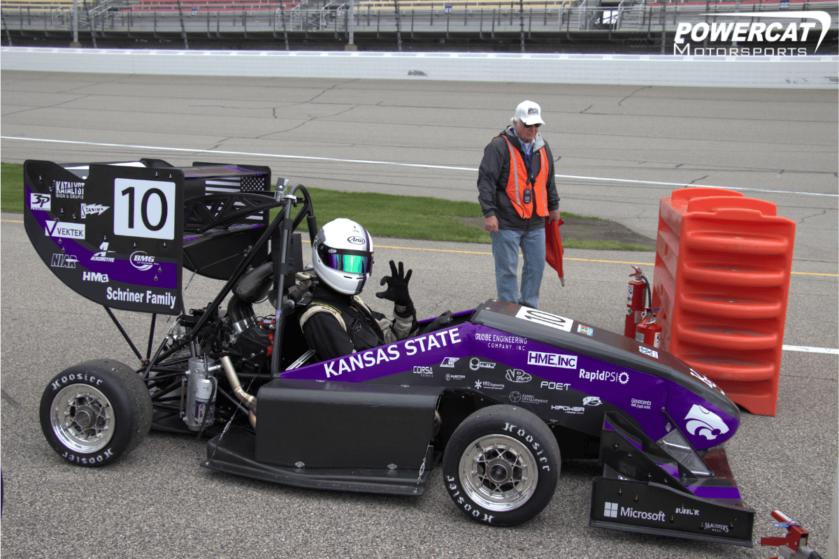 Suspension Lead and Chief Engineer throws up a powercat to the camera while waiting to practice for the day in Sphinx at Michigan Competition
