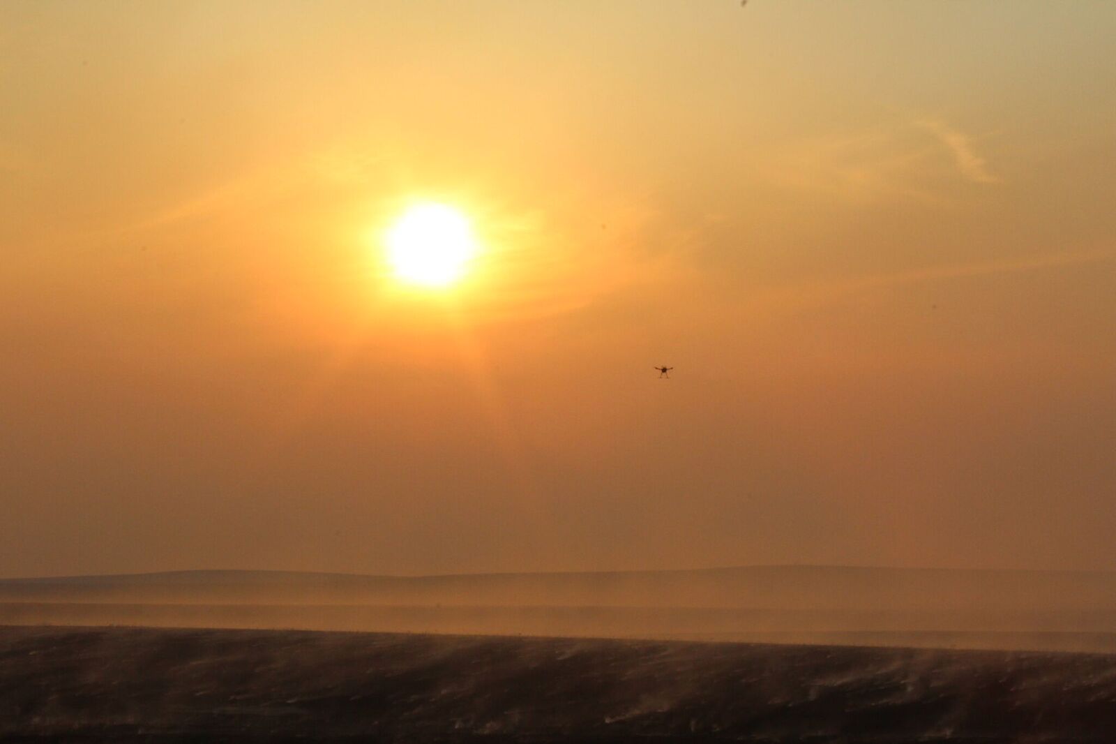An unmanned aircraft flies through the smoke over a tallgrass prairie prescribed burn as the sun sets. Kansas State University researchers have attached sensors on unmanned aircraft to gather air quality information during burns. | Photo credit: Douglas Watson, Kansas Department of Health and Environment