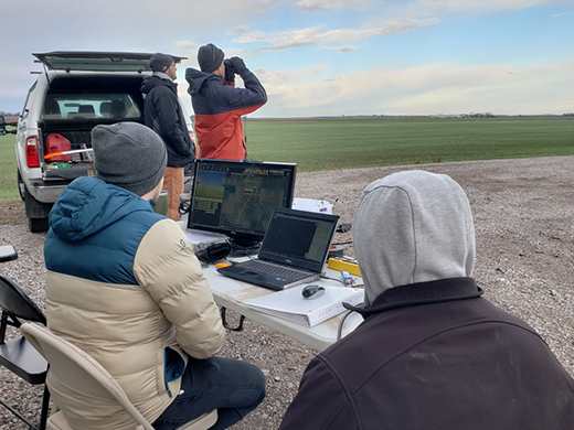 UAS students in the Advanced Fixed Wing Operations class perform a beyond visual line of sight flight, including a visual observer ensuring the airspace is clear and an air vehicle operator who is monitoring the aircraft at the ground control station. 
