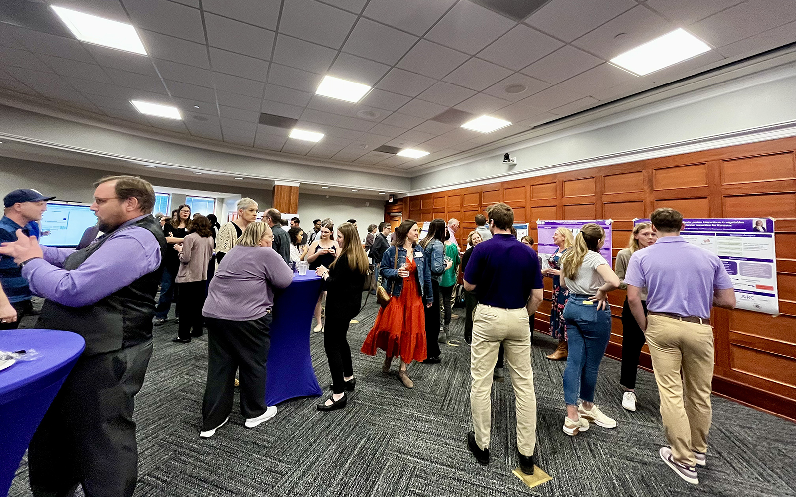Attendees visiting posters at a Posters, Pinot and Partnerships event.