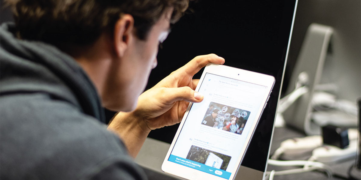 A person scrolls through social media on a tablet. 