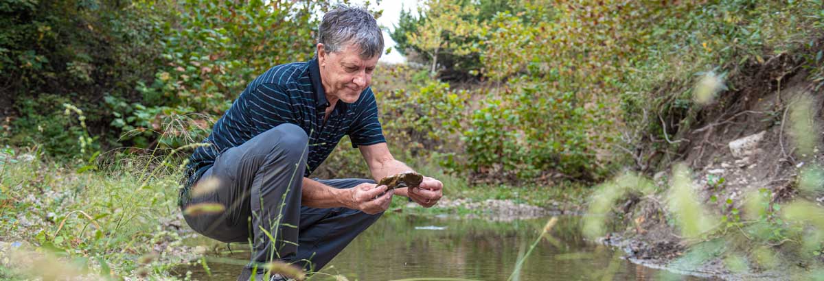 Walter Dodds looks at a rock that could have billions of microbes on it. 