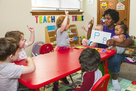 Child care provider Cheisa Myles helps children learn the alphabet.