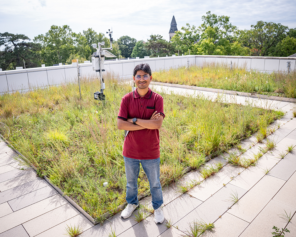 A man in a red shirt and jeans stands on a green roof