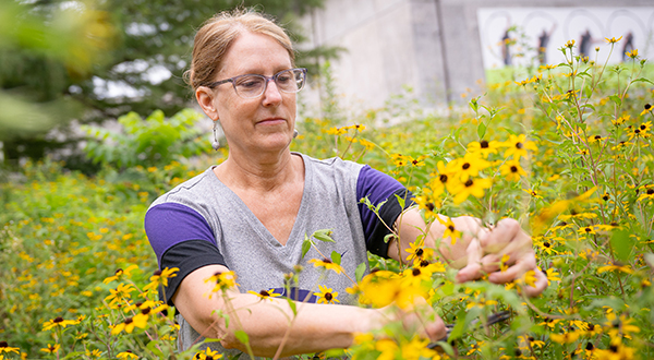 Woman in T-shirt poses near yellow flowers.