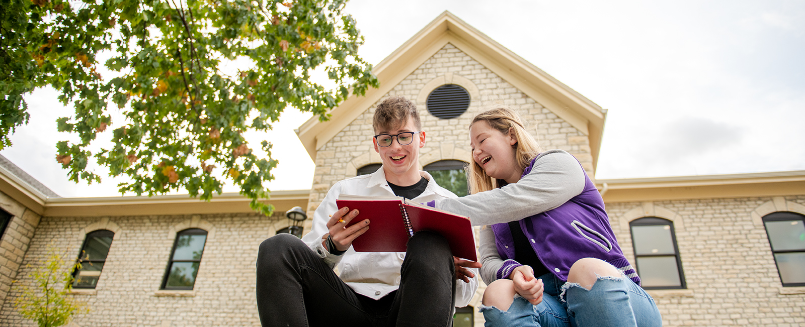 Pair of students sitting by Reigner looking at a notebook
