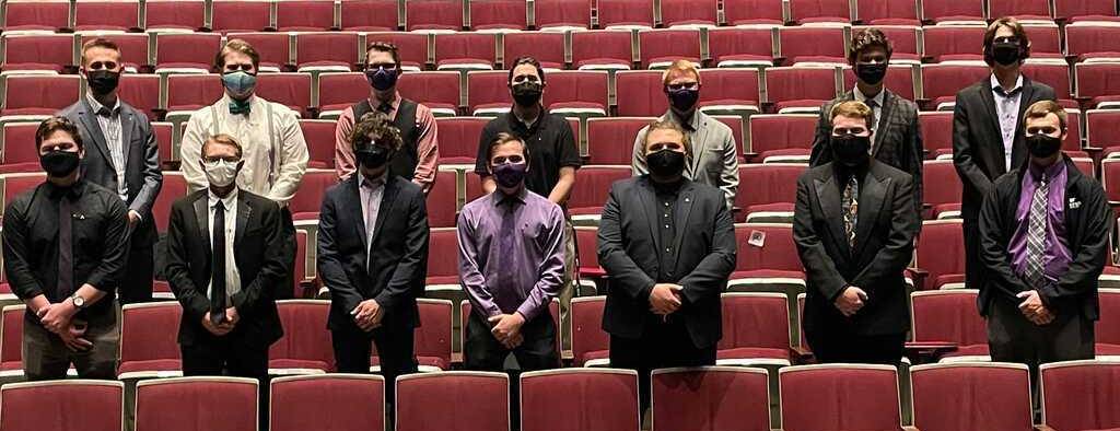 14 masked men stand in the seats of McCain auditorium