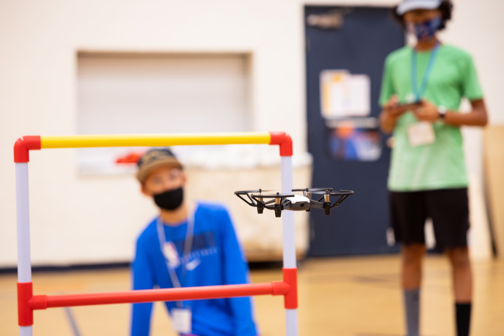 Two students working with a drone flying through a hoop