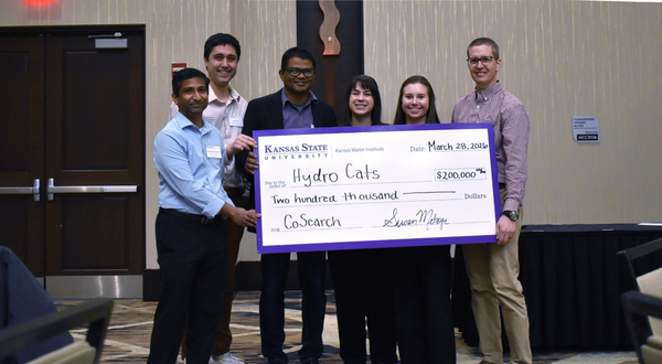 the winning team holds a big check