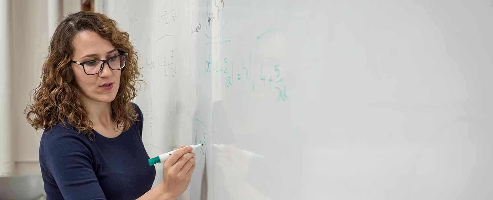 Graduate student demonstrating solving math equations on whiteboard